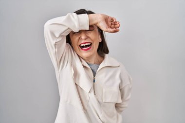 Orta yaşlı İspanyol kadın izole edilmiş arka planda duruyor. Gözleri kollarıyla kaplıyor. Neşeli ve komik gülümsüyor. kör kavram. 