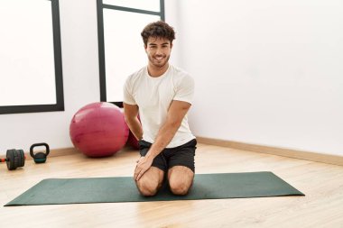 Genç İspanyol adam gülümsüyor spor merkezinde esniyor.