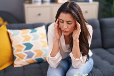 Evdeki kanepede oturan genç ve güzel İspanyol kadın stresli.