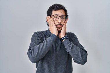 Handsome latin man standing over isolated background tired hands covering face, depression and sadness, upset and irritated for problem 