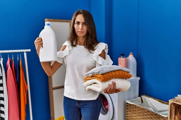 Young Hispanic Woman Doing Laundry Holding Detergent Bottle Skeptic Nervous — Fotografia de Stock