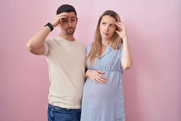 Casal Jovem Esperando Bebê Sobre Fundo Rosa Preocupado Estressado Sobre — Fotografia de Stock