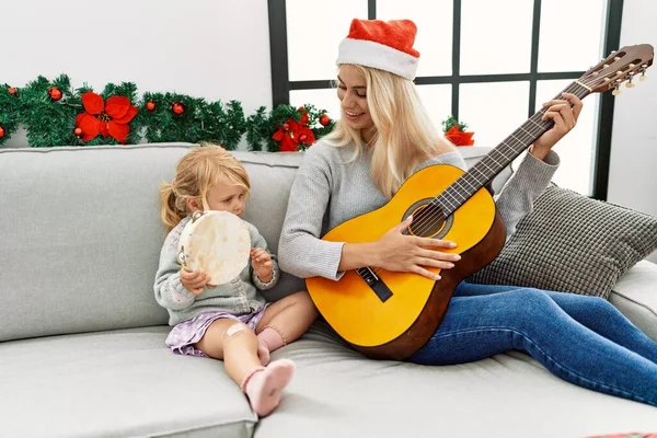 妈妈和女儿在家里坐在圣诞装饰旁边弹奏吉他和手鼓 — 图库照片