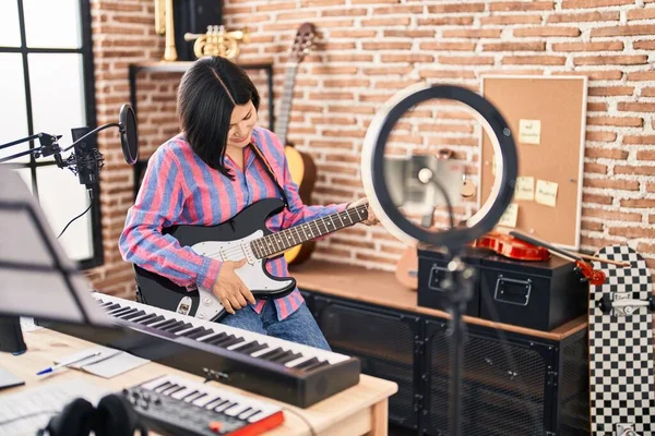 Young chinese woman artist having online electrical guitar class at music studio
