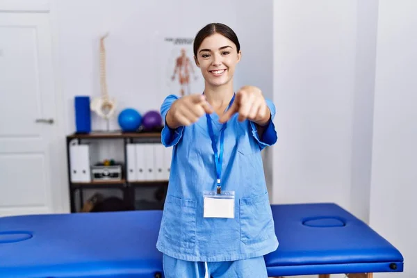 Mladá Hispánka Uniformě Fyzioterapeutky Stojící Klinice Ukazující Prstem Tebe Kameru — Stock fotografie
