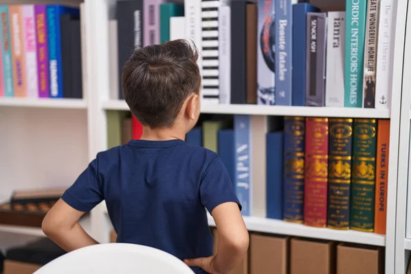 愛らしいヒスパニック系の幼児見ます本の棚で図書館学校 — ストック写真