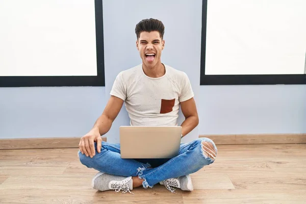 Young Hispanic Man Using Laptop Home Sticking Tongue Out Happy — Stockfoto
