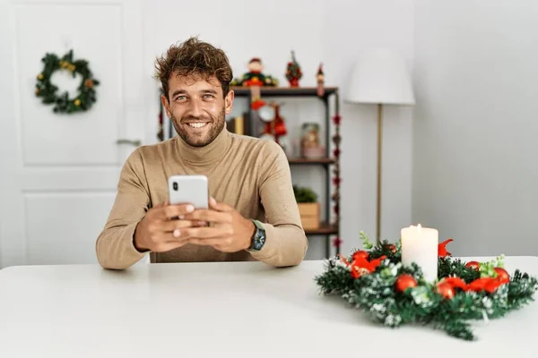 Jovem Hispânico Usando Smartphone Sentado Decoração Natal Casa — Fotografia de Stock