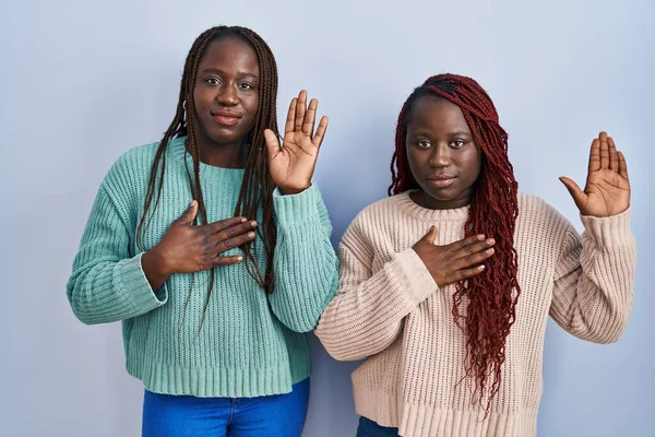 Dwie Afrykanki Stojące Nad Niebieskim Tłem Przeklinające Dłonią Piersi Otwartą — Zdjęcie stockowe