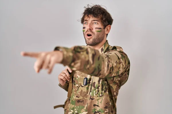 Hispanic Young Man Wearing Camouflage Army Uniform Pointing Finger Surprised — Foto de Stock