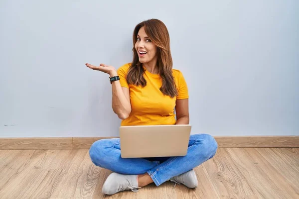 Hispanic Woman Using Laptop Sitting Floor Home Pointing Aside Hands —  Fotos de Stock