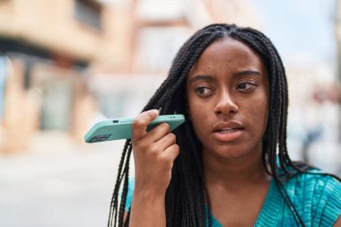 African american woman listening audio message by the smartphone at street