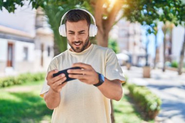 Parkta video oyunu oynayarak kendine güvenen İspanyol genç adam.