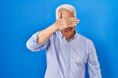 İspanyol kıdemli gözlüklü, gülümseyen ve gülümseyen bir adam. Gözleri kapayarak şaşkınlık yaratıyor. kör kavram. 