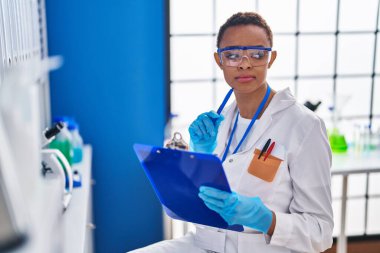 Afrika kökenli Amerikalı kadın bilim adamı laboratuvarda şüpheli ifadelerle belge yazıyor.