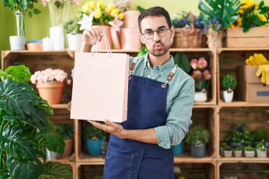 Handsome hispanic man working at florist shop looking at the camera blowing a kiss being lovely and sexy. love expression. 