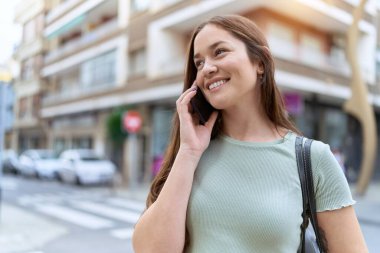 Genç, güzel bir kadın, gülümsüyor. Kendine güveniyor. Akıllı telefondan konuşuyor.