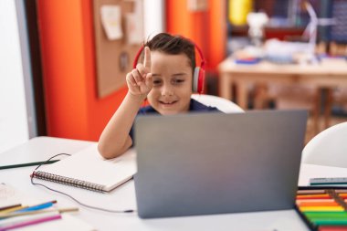 Sınıfta bilgisayar ve kulaklık kullanan sevimli İspanyol çocuk öğrenci.