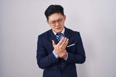 Young asian man wearing business suit and tie suffering pain on hands and fingers, arthritis inflammation 