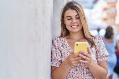 Sokakta akıllı telefon kullanan kendine güvenen genç bir kadın.