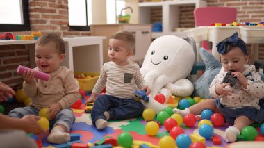 Anaokulunda yerde oturmuş oyuncaklarla oynayan bir grup çocuk.