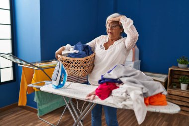 Orta yaşlı kadın çamaşır odasında ev işleri yaparken strese girdi.