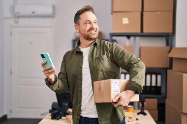 Kafkasyalı genç bir iş adamı ofiste akıllı telefon paketi kullanıyor.