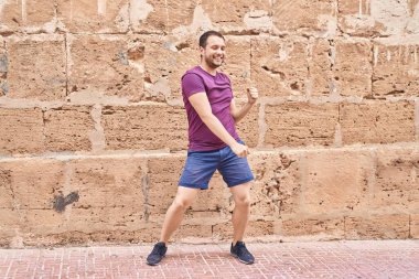 Genç adam gülümsüyor, sokakta dans ediyor.