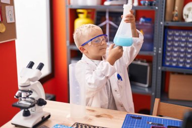 Sınıfta elinde test tüpü tutan sevimli bir çocuk.
