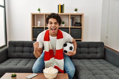 Genç İspanyol adam futbol maçı izliyor ve takımını evde destekliyor..