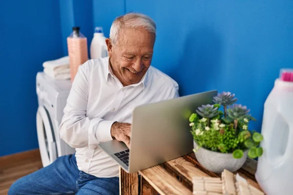 老年人在洗衣房用笔记本电脑等洗衣机 — 图库照片