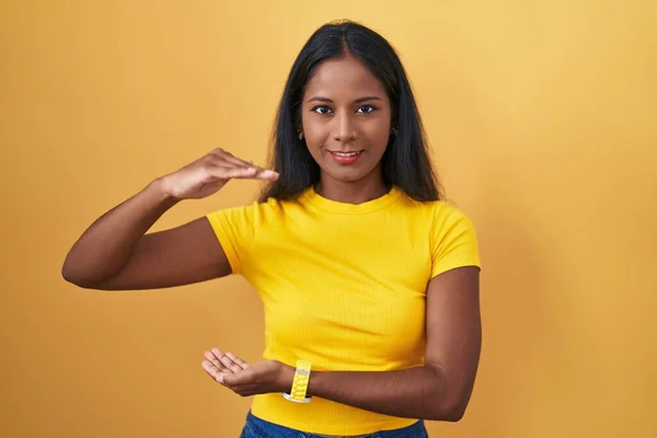 Młoda Hinduska Kobieta Stojąca Nad Żółtym Tłem Gestykulująca Dłońmi Pokazującymi — Zdjęcie stockowe