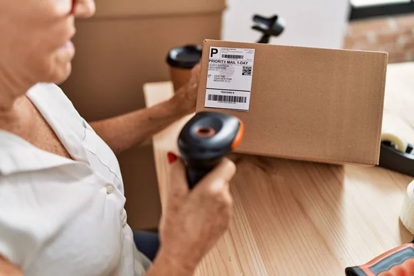 stock image Senior grey-haired woman business worker scanning package label at office