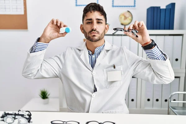 Young Optician Man Holding Glasses Contact Lenses Relaxed Serious Expression — Stock Photo, Image