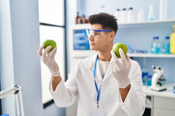 Young Hispanic Man Wearing Scientist Uniform Holding Apples Laboratory — ストック写真