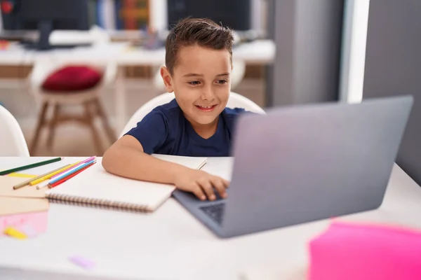 stock image Adorable hispanic toddler student using laptop sitting on table at classroom