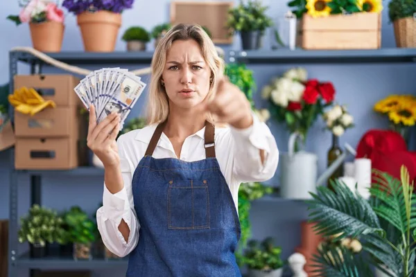 Young Blonde Woman Working Florist Shop Holding Dollars Pointing Finger — Stockfoto
