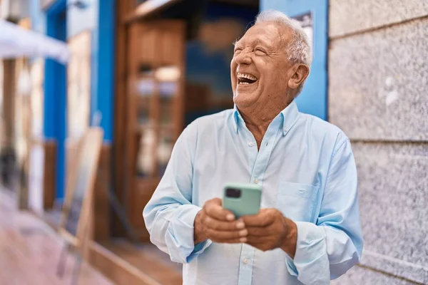 年长的白发男子在街上用智能手机自信地微笑 — 图库照片