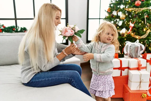妈妈和女儿手里拿着一束鲜花 坐在圣诞树旁 — 图库照片