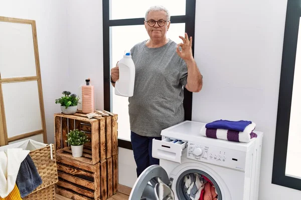 Senior Caucasian Man Doing Laundry Holding Detergent Bottle Doing Sign — Stock Photo, Image