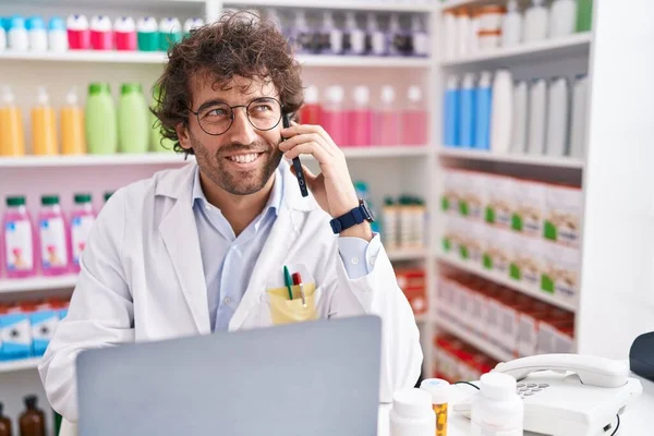 Young Hispanic Man Pharmacist Talking Smartphone Using Laptop Pharmacy — Fotografia de Stock