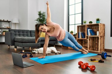 Evde yoga dersi aldığı için kendinden emin gülümseyen genç bir kadın.