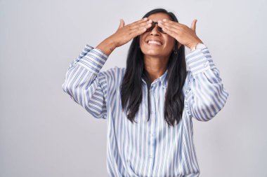 Young hispanic woman wearing glasses covering eyes with hands smiling cheerful and funny. blind concept. 