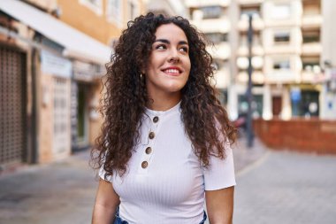 Young beautiful hispanic woman smiling confident looking to the side at street