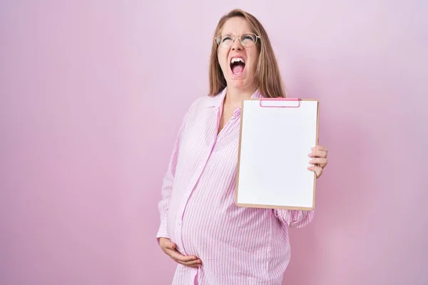 Young Pregnant Woman Holding Clipboard Angry Mad Screaming Frustrated Furious — Foto de Stock