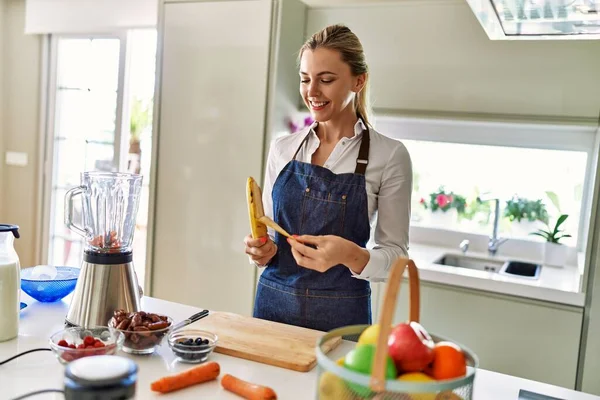 Joven Mujer Rubia Sonriendo Seguro Pelando Plátano Cocina —  Fotos de Stock