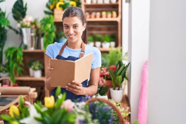 Çiçekçiye gülümseyen güzel İspanyol kadın çiçekçiye not defteri okuyor.