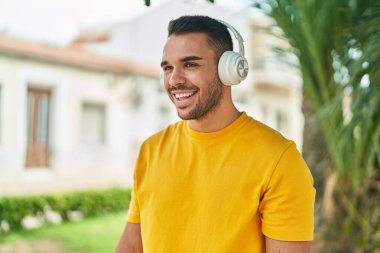 Genç İspanyol adam parkta müzik dinliyor.