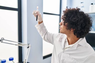 Laboratuvarda kan testi tüpü analizi yapan bilim adamı üniforması giyen genç bir İspanyol.