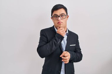 Down sendromlu genç İspanyol adam iş stili giyiniyor kameraya kendinden emin bakıyor kollarını kavuşturmuş ve çenesini kaldırmış bir şekilde gülümsüyor. Olumlu düşünmek. 